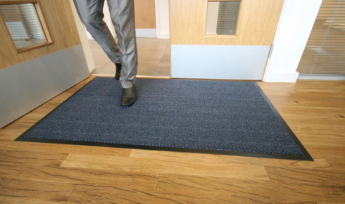 How can placing mats both outside and inside entrances protect floors from grit